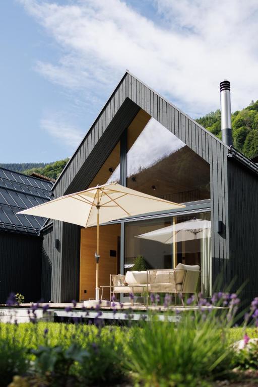 a house with a patio with an umbrella and chairs at Zalbander Chalets in Silbertal