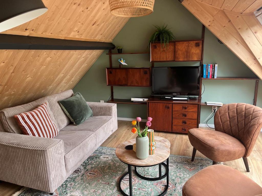 a living room with a couch and a tv at Gastenverblijf Boven De S l a g e r i j in Schijndel