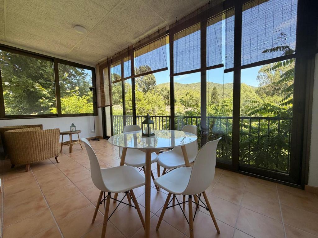 a dining room with a table and chairs and windows at La Sabonnera in Sant Llorenç de la Muga