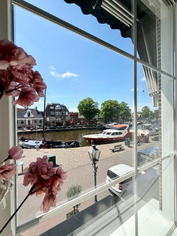a window with a view of a boat in a harbor at Maison Bo Luxury Stay in Historic Lemmer in Lemmer