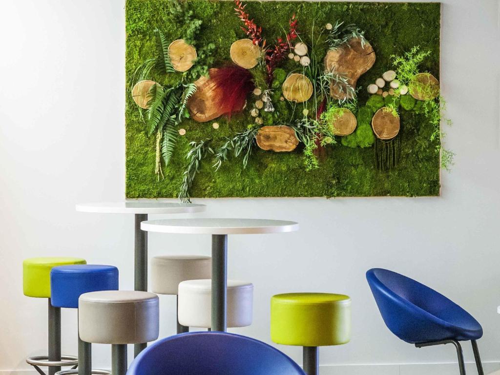a painting of a vase of flowers on a wall at Ibis Budget Château-Thierry in Essômes-sur-Marne