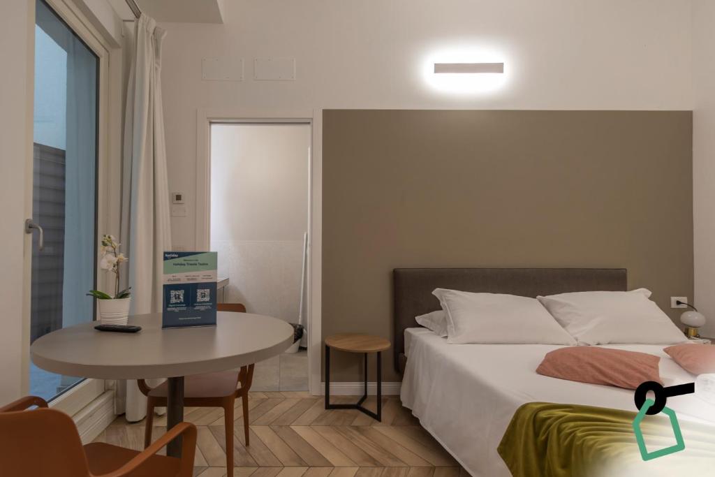 a bedroom with a bed and a table and a window at Hotiday Trieste Teatro in Trieste