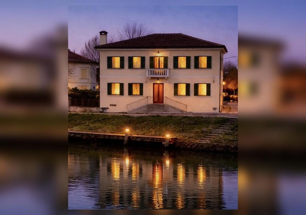 a large white house with lights on the water at Villa Venezia Apartment in Dolo