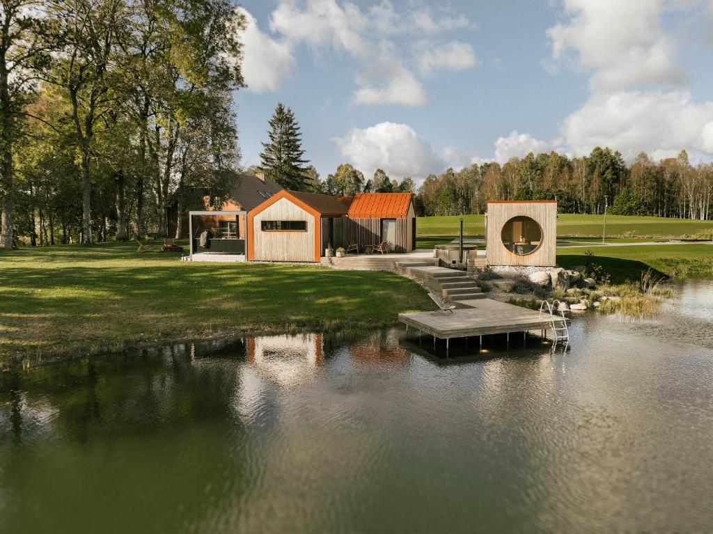 a house with a dock next to a body of water at Lėtai resort, Lakefront Nature Stay with Sauna in Eželiškės