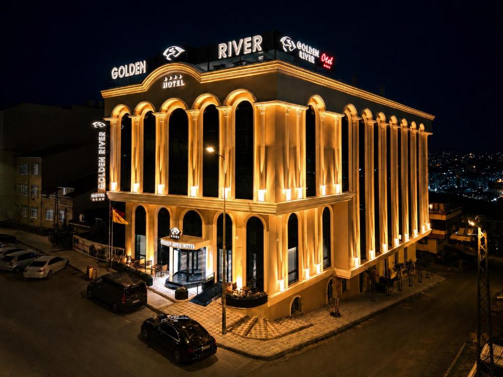 a building lit up at night with cars parked in front at Golden River Hotel By Continent in Arnavutköy