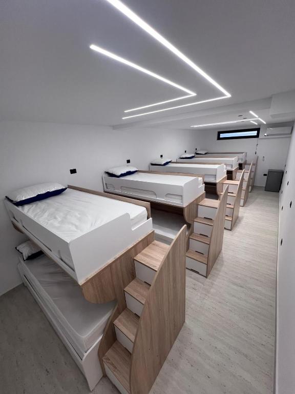 a row of beds in a room with wooden floors at Ferra Hostel in Durrës