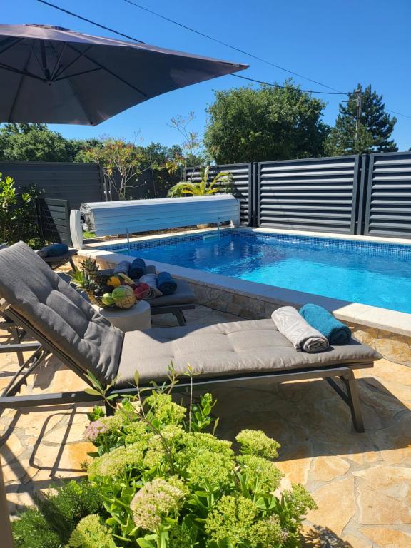 a swimming pool with an umbrella and chairs next to it at Villa AMore Radini with a private heated saltwater pool and private parking in Brtonigla