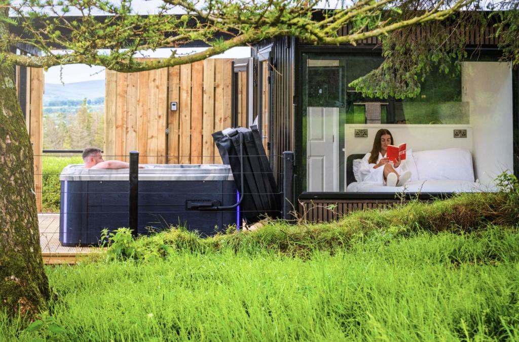 a man and a woman reading a book in a tiny house at Umry-Calm Farm Stays in Feeny