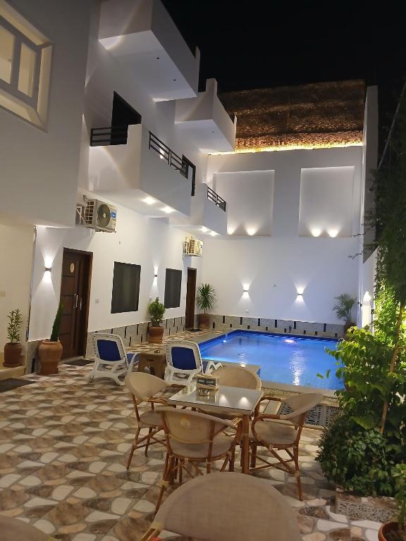 a pool room with tables and chairs and a swimming pool at NOOR SEEN House in Luxor