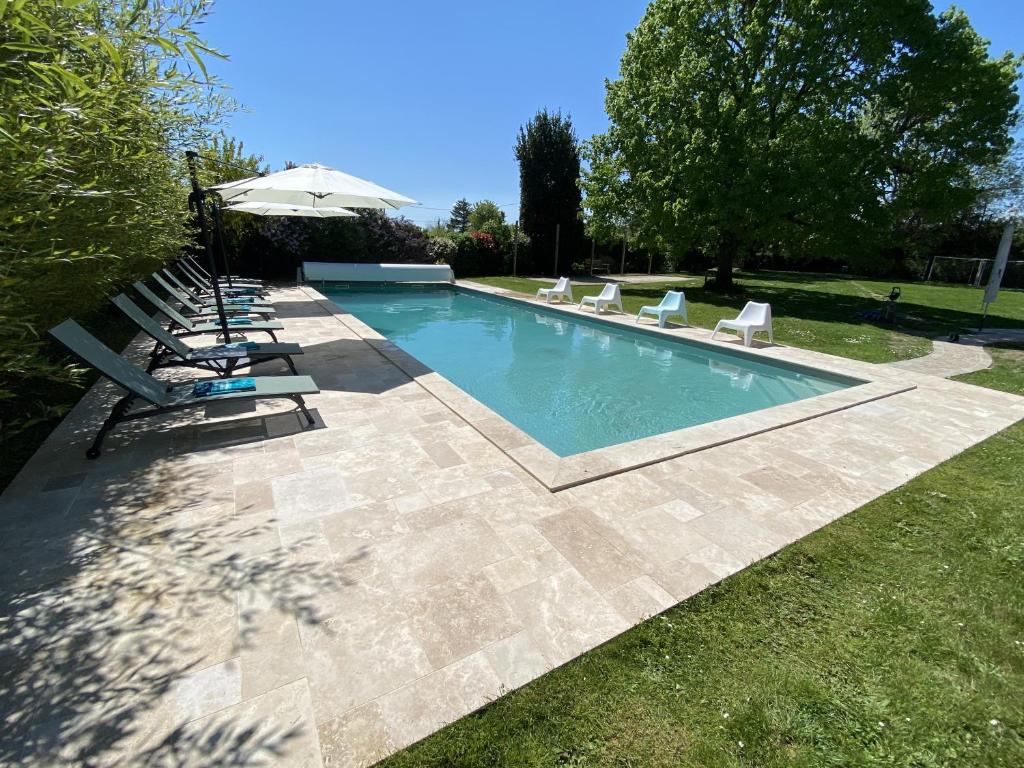 a swimming pool with lounge chairs and an umbrella at La Corti in Tillières-sur-Avre