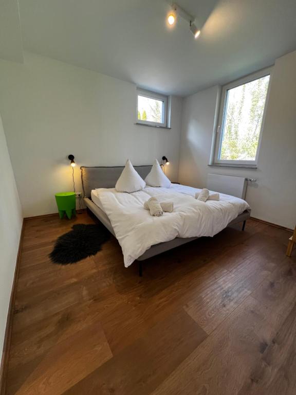 a bedroom with a bed with white sheets and two windows at Oase in Hürth