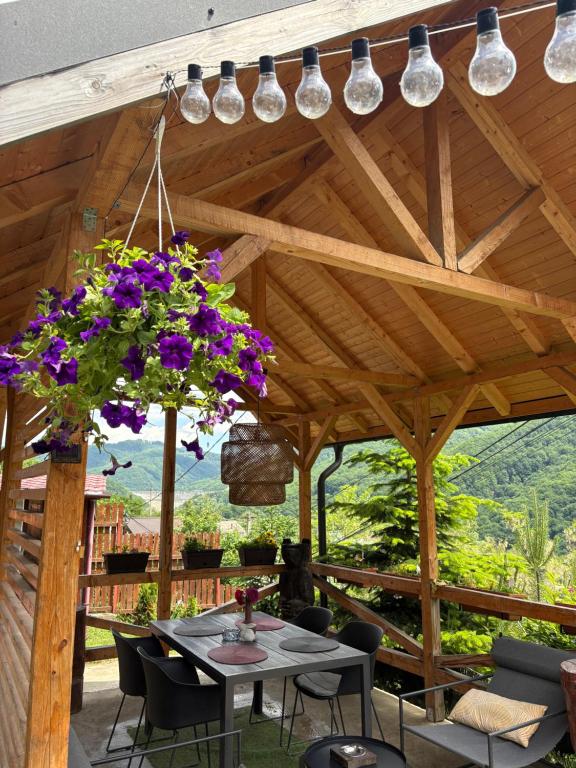 a patio with a table with purple flowers and lights at Chalet Husky-Pet Friendly&Private in Şotrile