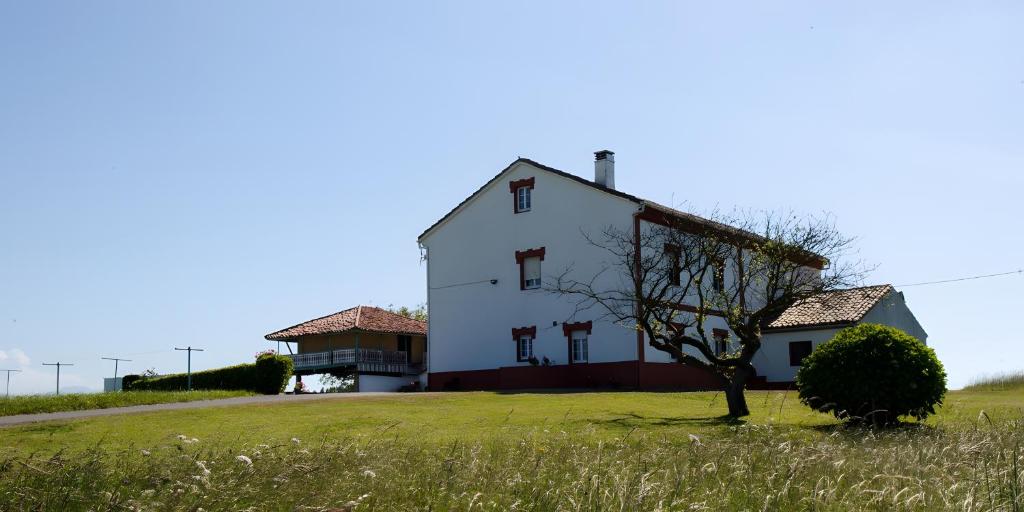 a white house on a hill with a tree in a field at Finca El Carbayal in El Campo