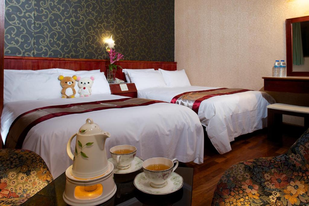 een hotelkamer met 2 bedden en 2 kopjes koffie bij Gene Long Haiy Att Hotel in Chiayi City
