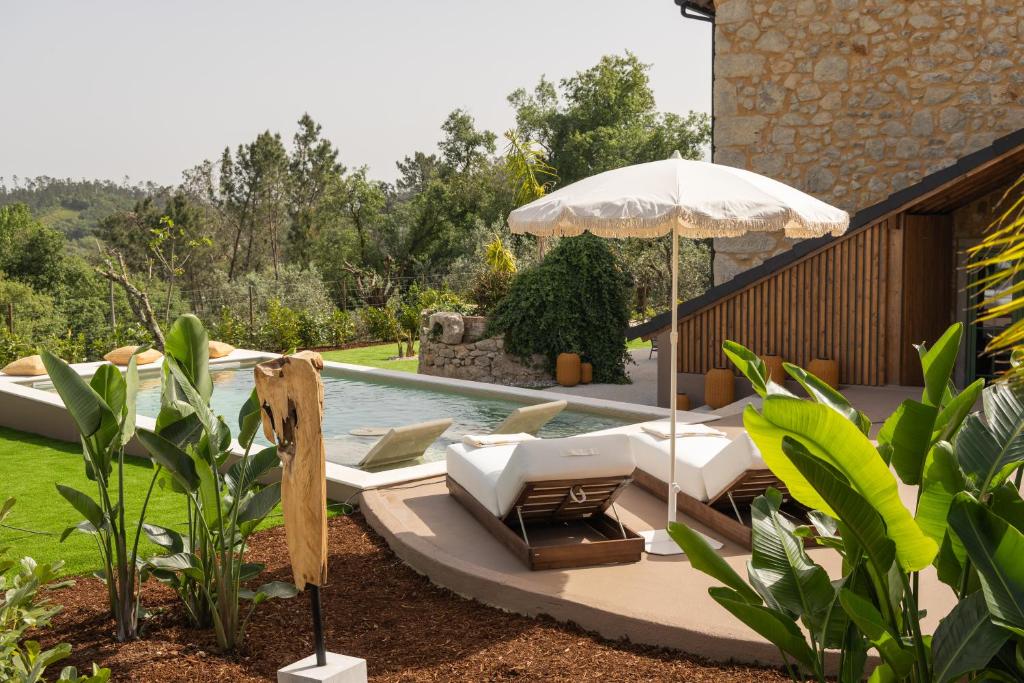 a pool with two lounge chairs and an umbrella at BaguHouse in Pombal