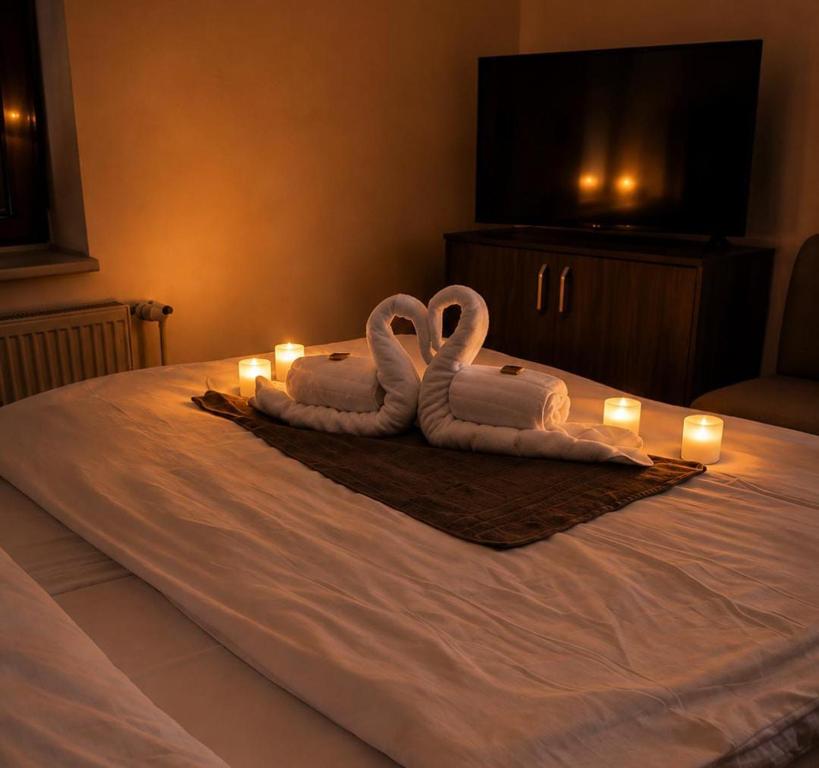 two towel swans sitting on a bed with candles at Hotel Orka in Moravská Třebová