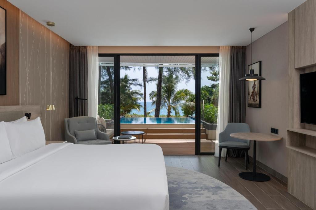 a bedroom with a bed and a view of a pool at Radisson Blu Resort, Phuket Mai Khao Beach in Mai Khao Beach