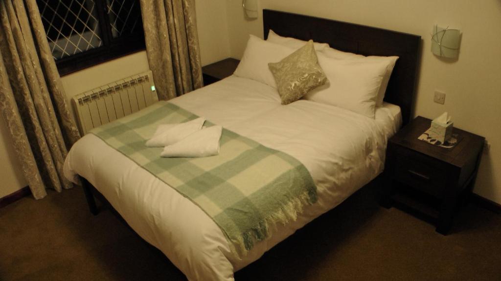 a bed with a green and white blanket and pillows at Bay Lodge in Birchington
