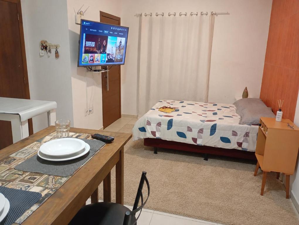 a room with a bed and a table with a television at Suíte Completa in Barra Velha