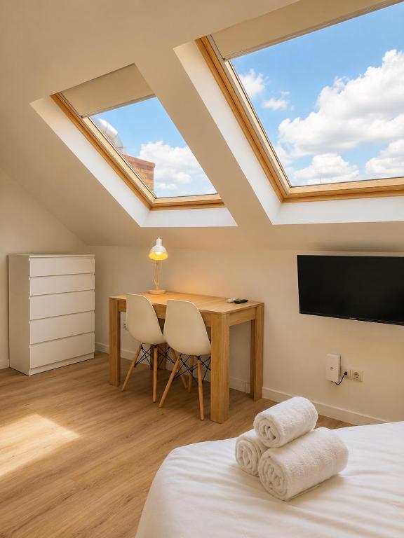 a bedroom with a skylight and a table and a desk at Aparthotel Fuenlabrada Central in Fuenlabrada