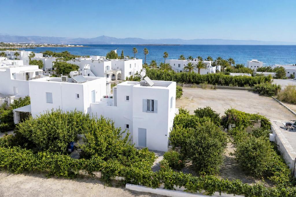 an aerial view of a white house with the ocean at Flora & Agelos Studios - Paros in Chrissi Akti
