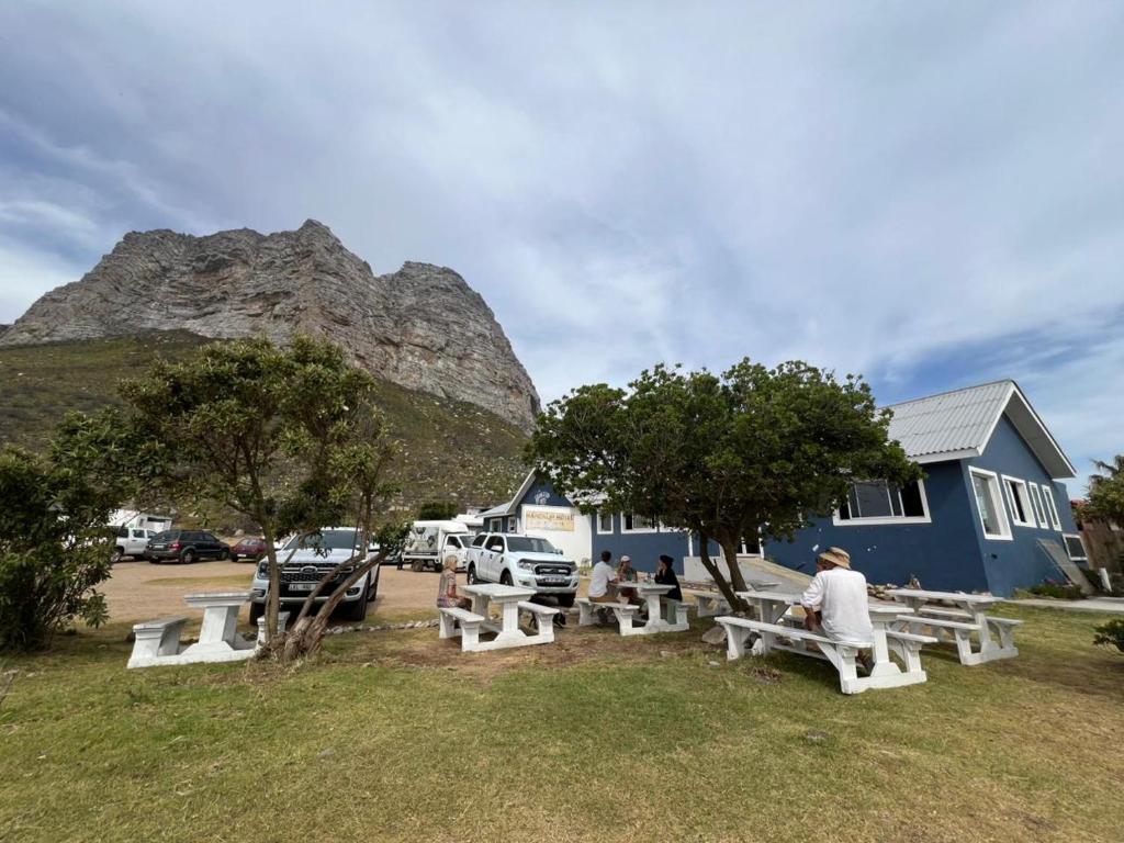 a group of people sitting at picnic tables in front of a mountain at The Hangklip Hotel in Pringle Bay