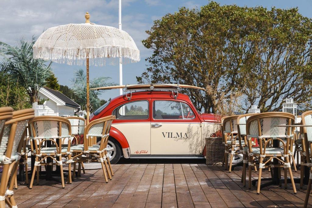 a red and white van with chairs and an umbrella at Vilma Sjøbad in Filtvet