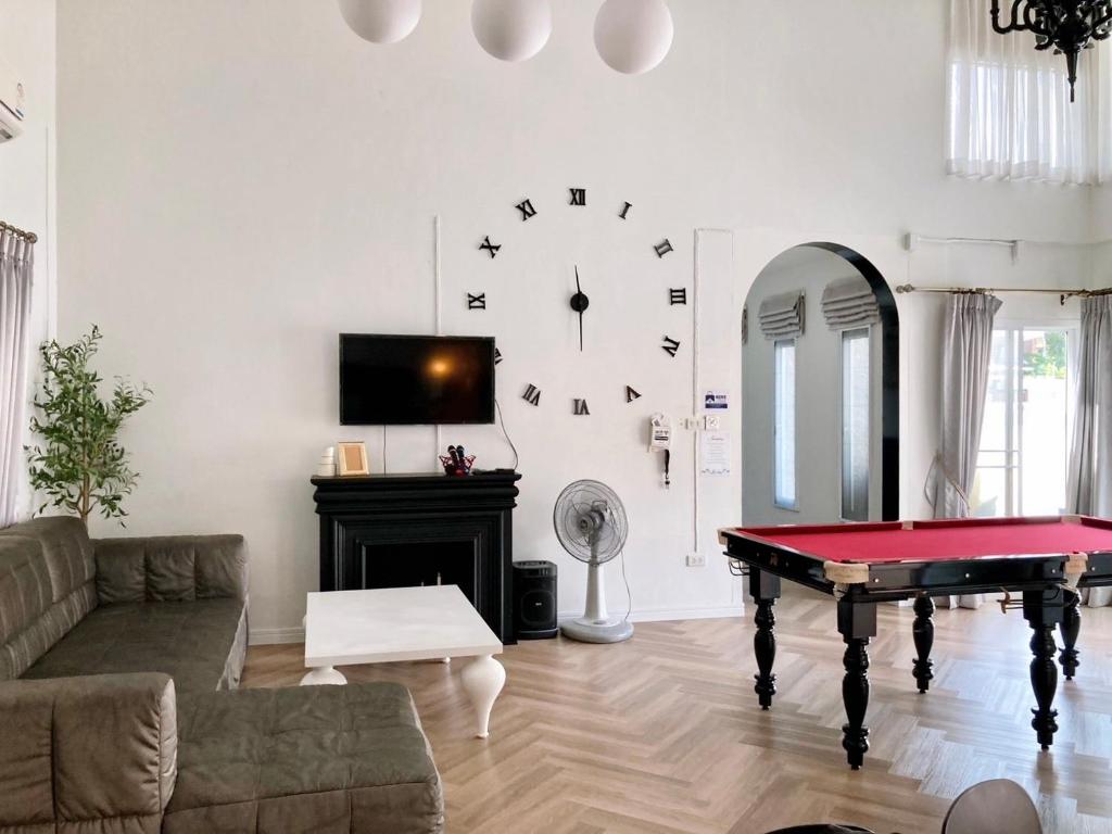 a living room with a table and a clock on the wall at Nadda Pool Villa Ranong in Ban Bang Rin (1)