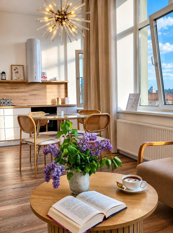 a living room with a table with a book and purple flowers at Sun Shine 1 apartment in Liepāja