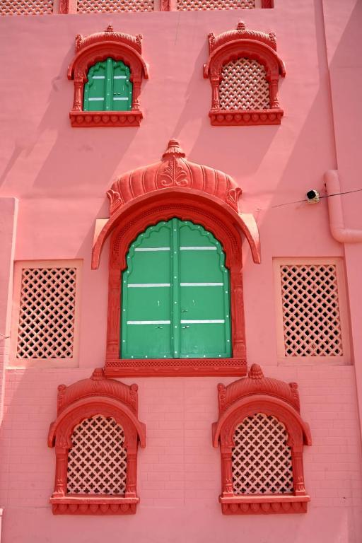 a pink building with three green windows at Ardas Villa Bikaner - Heritage Luxury Boutique Stay, With Free Pick Up and Drop in Bikaner