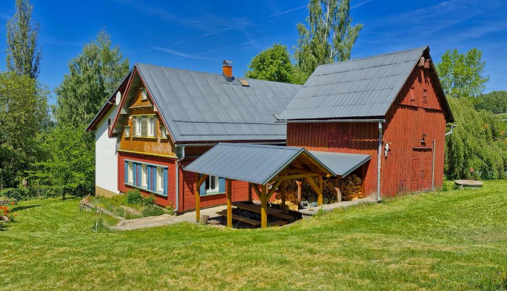 a red barn with a metal roof on a field at Chalupa Šumburk in Svárov