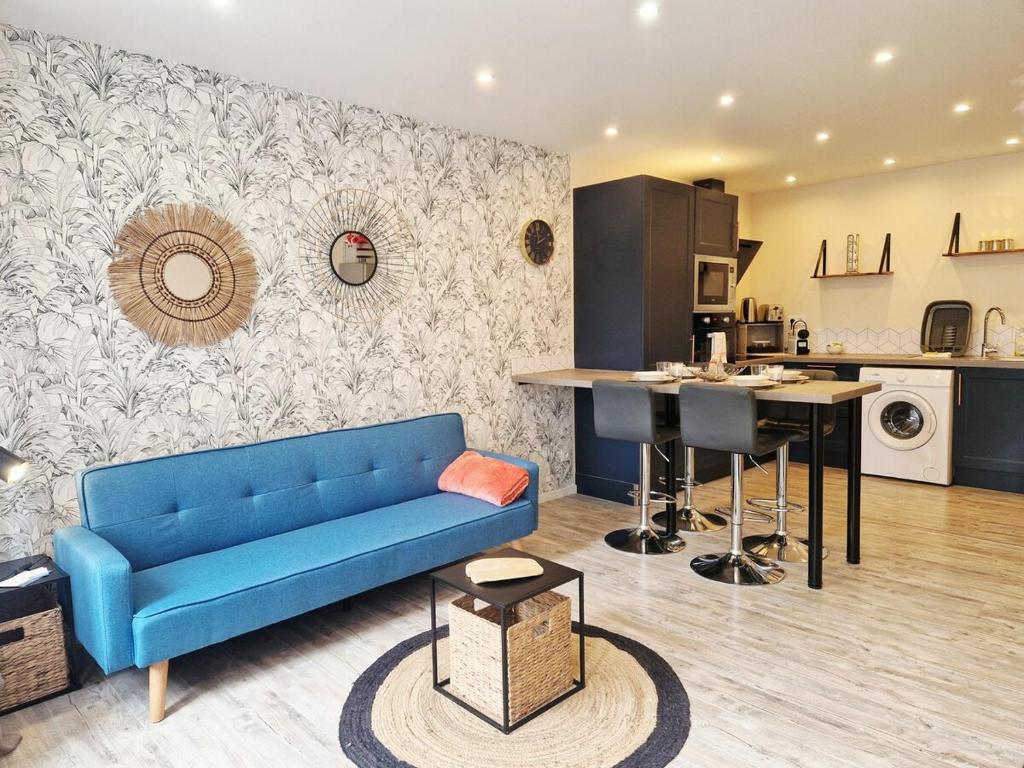 a living room with a blue couch and a kitchen at Le Key Largo in Cherbourg en Cotentin