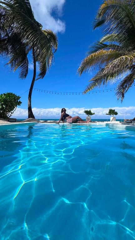 a woman laying in a swimming pool next to a palm tree at Mango Beach House in Jambiani