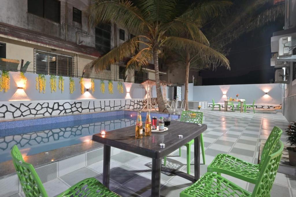 a patio with a table and chairs next to a pool at II EMPYREAN STAYS II AURA VILLA II 3BHK II AC II LARGE POOL Il in Lonavala