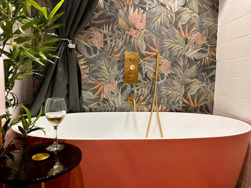 a bath tub in a bathroom with a glass of wine at Romantic Boutique Cottage with pink roll-top bath-Hastings Old Town in Hastings