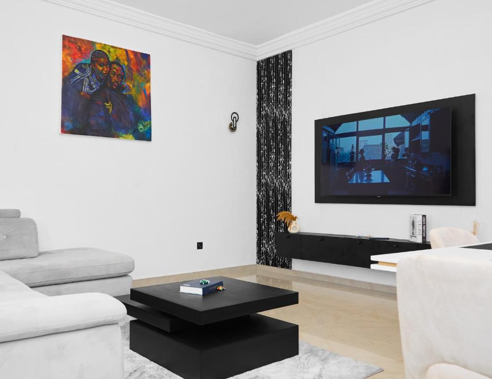 a white living room with a white couch and a tv at IGBADUN House in Godomey