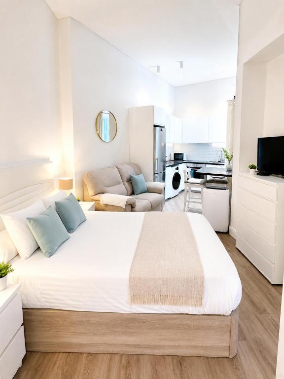 a white bedroom with a large bed and a kitchen at Grand Central House - Deluxe Studio - GibraltarStay Apartments in Gibraltar
