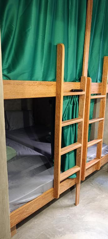 a bunk bed with a ladder and a green sheet at Book a bed Jacumã in Conde