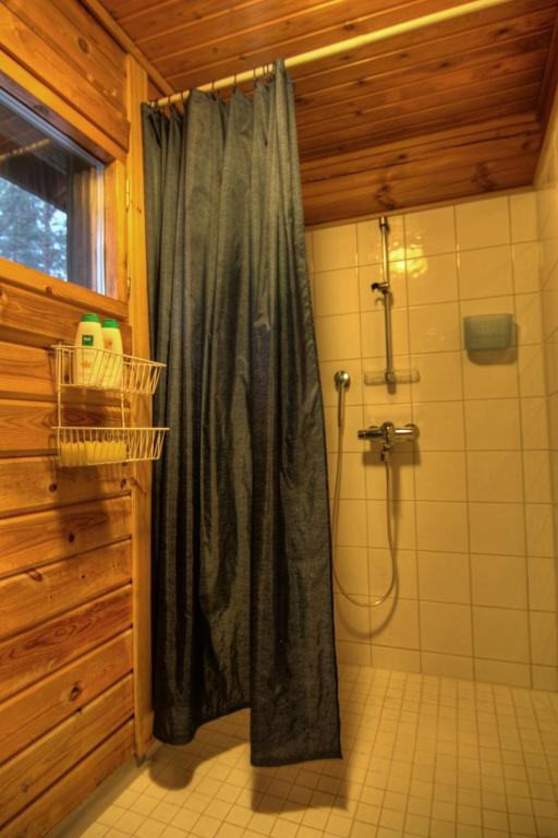 a shower with a black shower curtain in a bathroom at Kutusumppu A in Tahkovuori