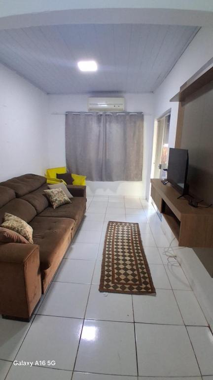 a living room with a couch and a television at Casa de férias Pôr do Sol 4 in Bataguaçu