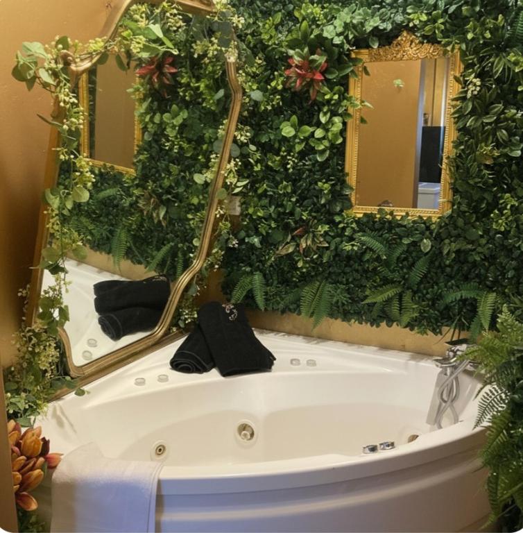 a bath tub with a green wall with mirrors at Visconti suite and spa in Catania