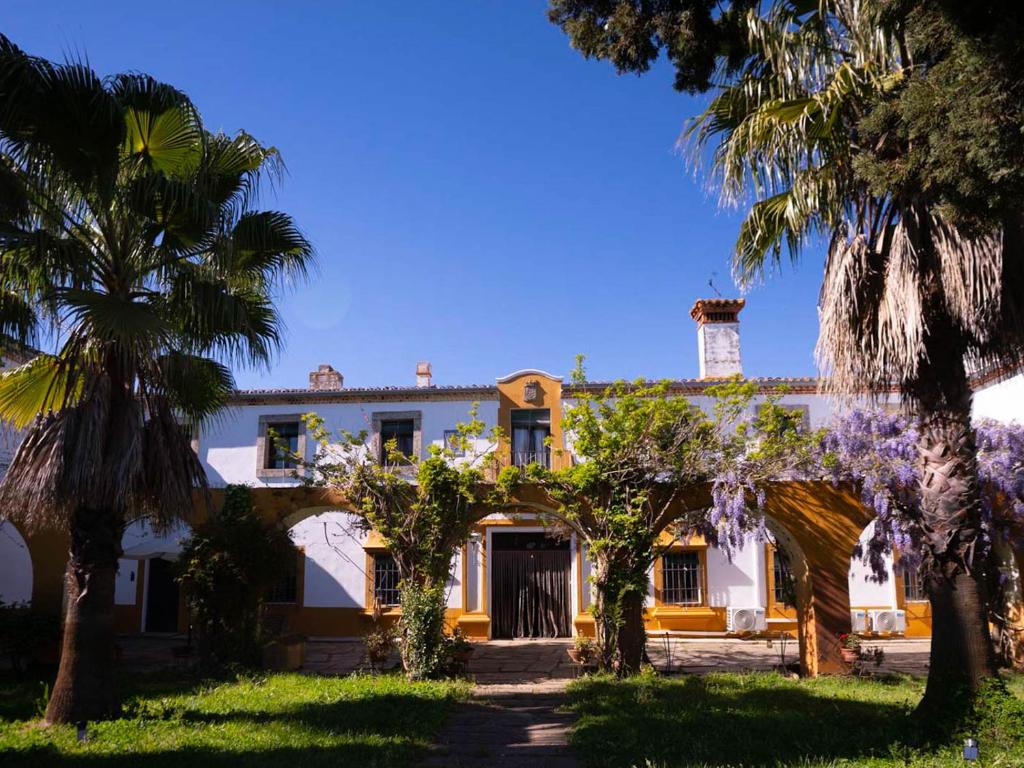 a house with palm trees in front of it at Cortijo Negretti in Herrera de Alcántara