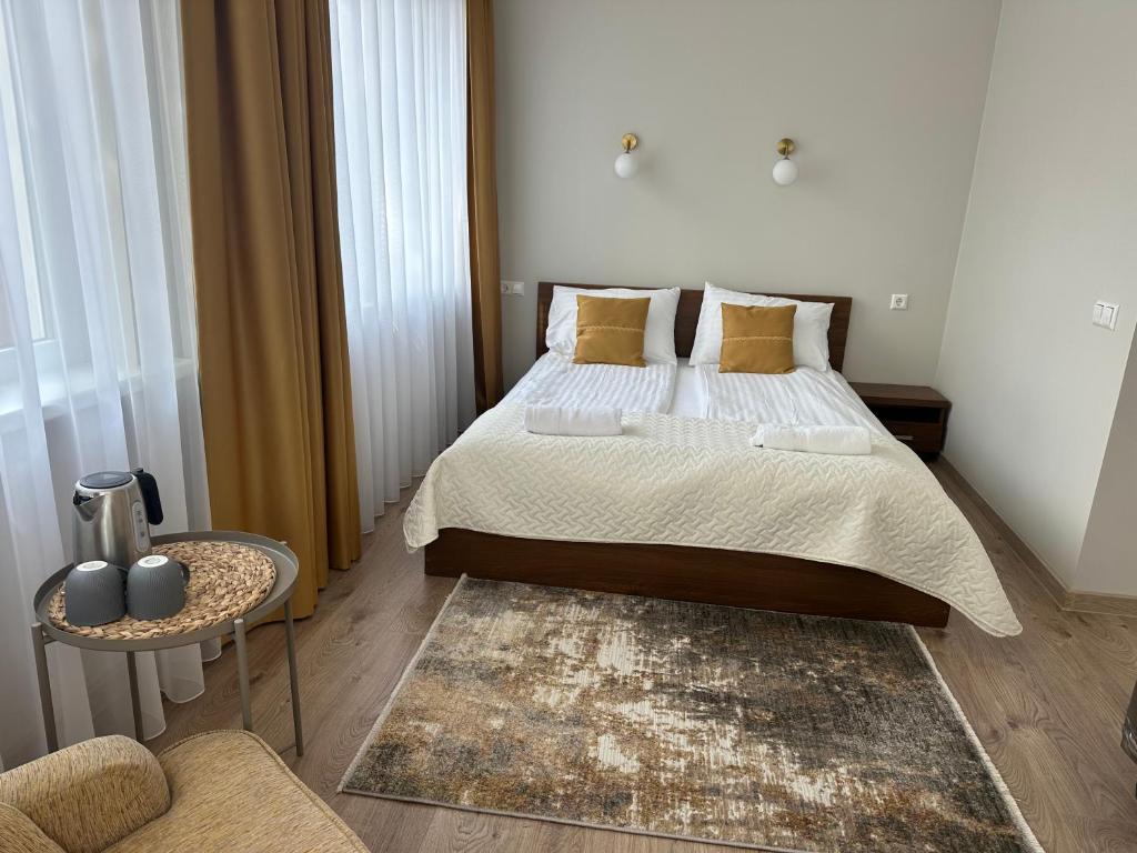 a bedroom with a large bed and a chair at NB Apartamentai in Palanga