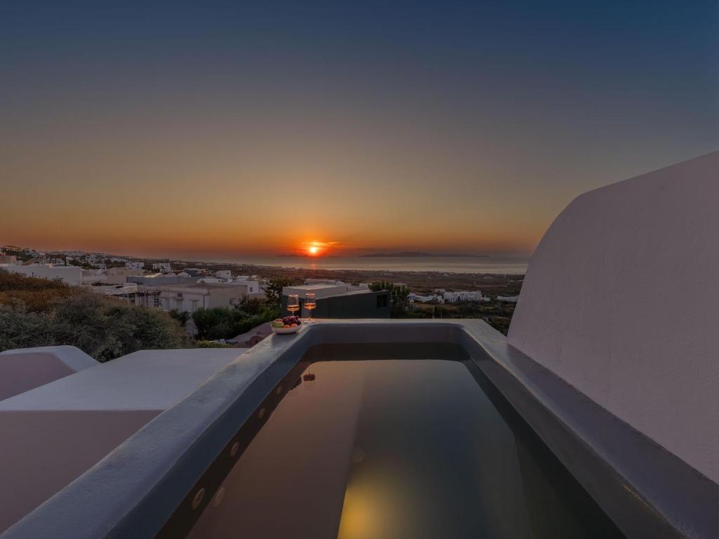 a sunset from the roof of a house with a swimming pool at Elios Cave Suites in Oia