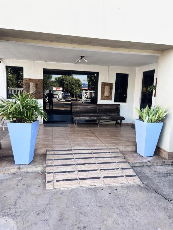 a patio with a bench and two potted plants at Hotel Ceolatto in Várzea Grande