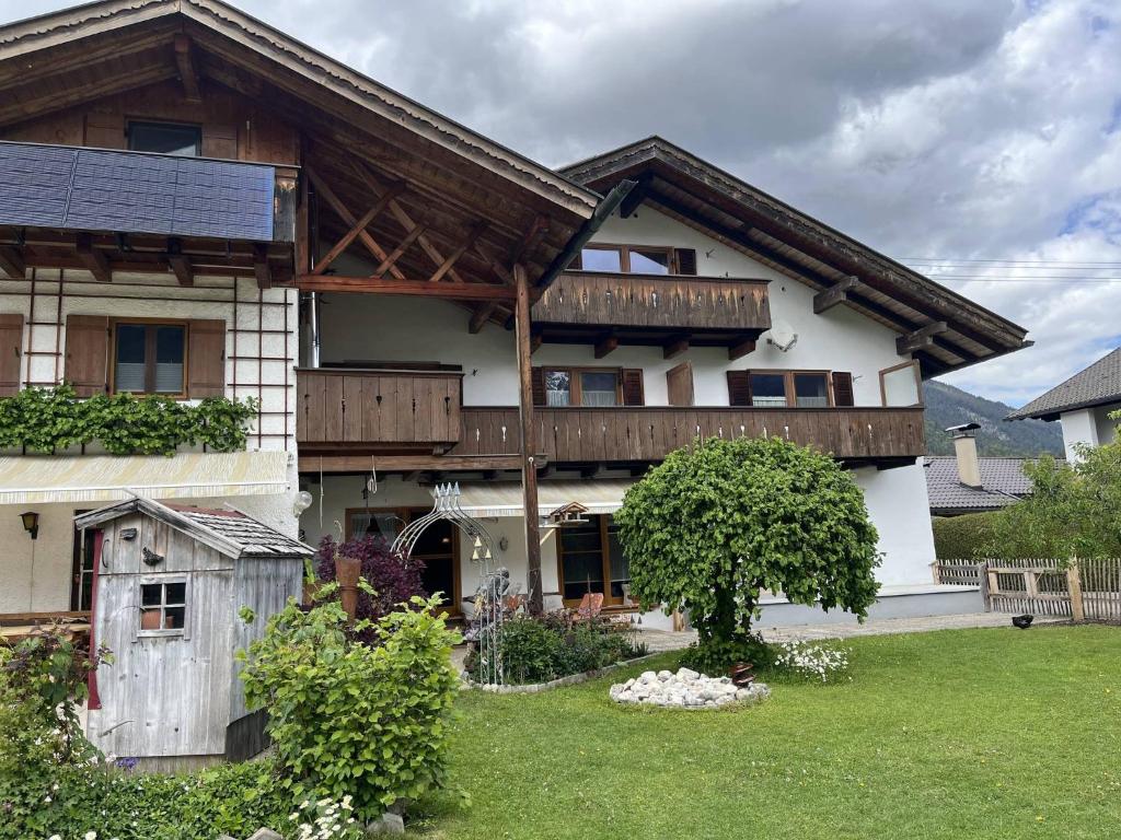 a house with a wooden roof and a yard at Ferienwohnung 2 Am Krepbach in Grainau