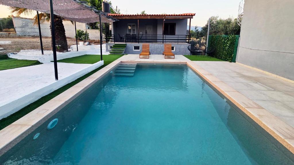 a swimming pool with two orange chairs in front of a house at Dolce Far Niente Greece in Agioi Theodoroi