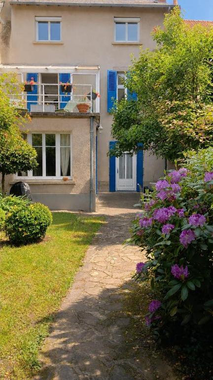 a house with blue doors and flowers in front of it at Maison familiale en centre bourg in Ahun