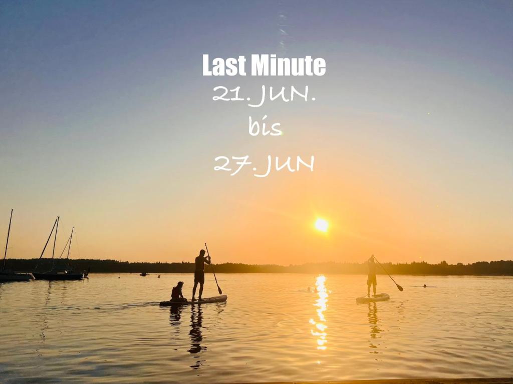 due persone stanno facendo paddleboard su un lago al tramonto di simsseeLOFT - Ferienapartments in Baierbach am Simssee a Stephanskirchen