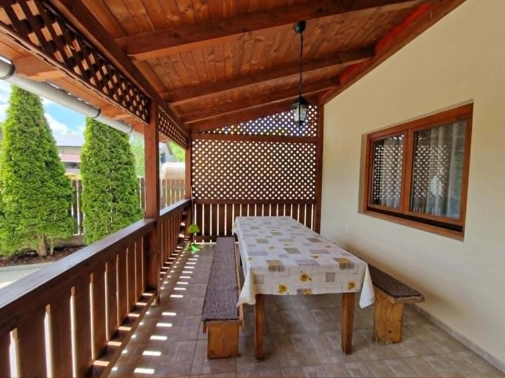 a wooden porch with a table on a deck at Akácpatak Vendégház in Lupeni